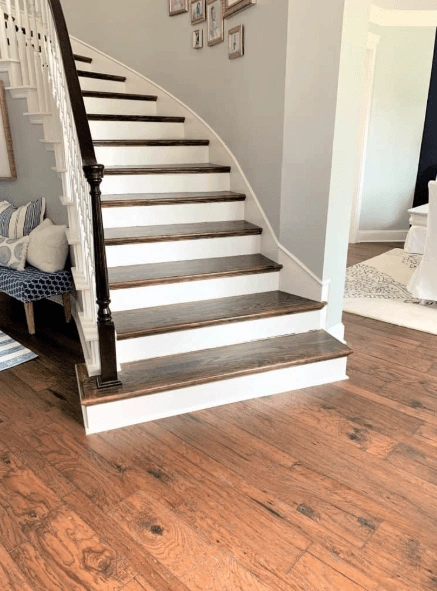 Stained hardwood stair treads over painted risers beside a hardwood floor