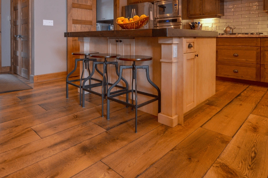 Wide-plank oak flooring with heavy grain running past a kitchen island